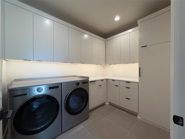 clothes washing area with cabinets, independent washer and dryer, and light tile patterned floors