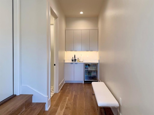 hall with wine cooler, wood-type flooring, and sink