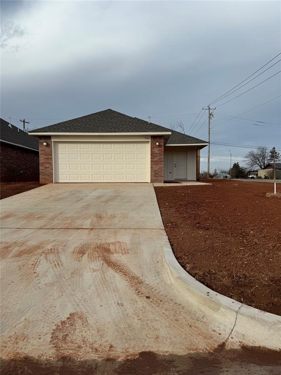 ranch-style house featuring driveway, brick siding, roof with shingles, and an attached garage