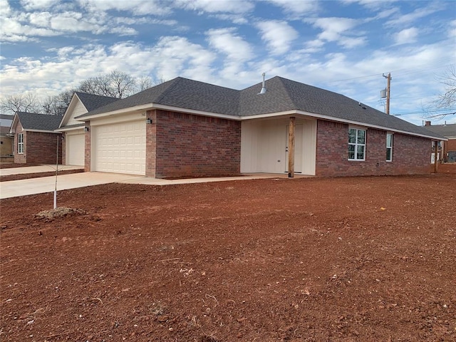 view of front of home with a garage, brick siding, driveway, and roof with shingles