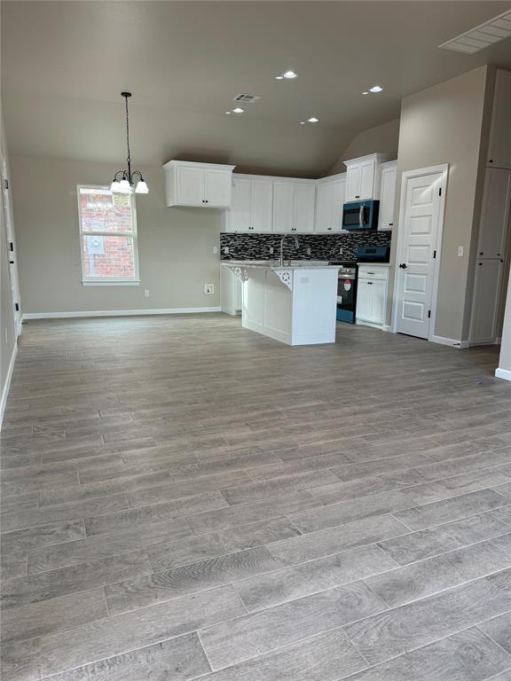 kitchen featuring white cabinetry, a kitchen island, stainless steel range, and lofted ceiling