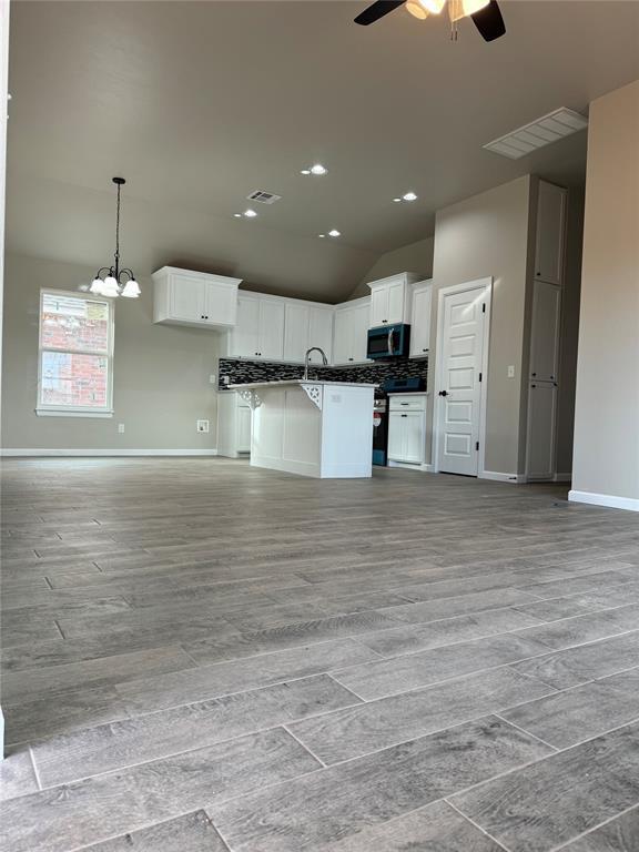 kitchen featuring white cabinetry, pendant lighting, a kitchen island, and appliances with stainless steel finishes