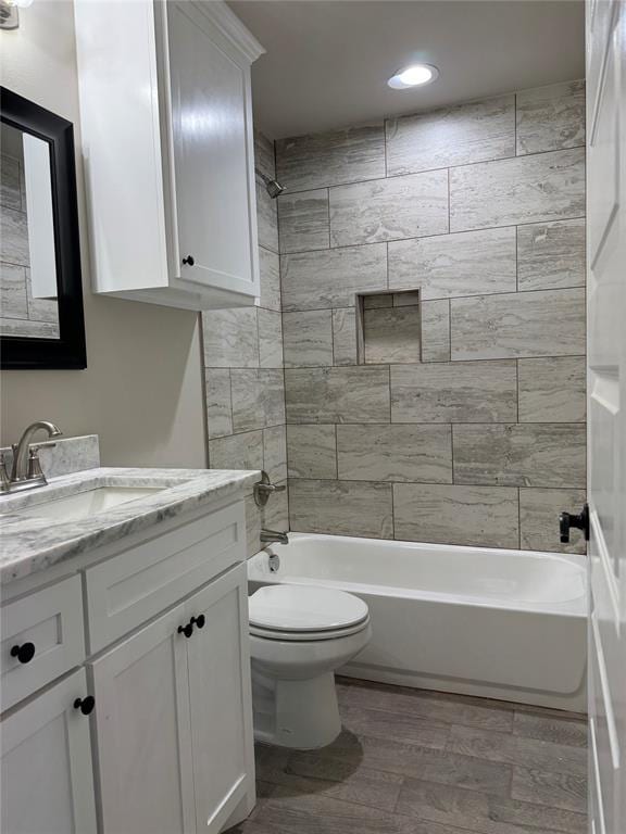 full bathroom with vanity, hardwood / wood-style floors, toilet, and tiled shower / bath