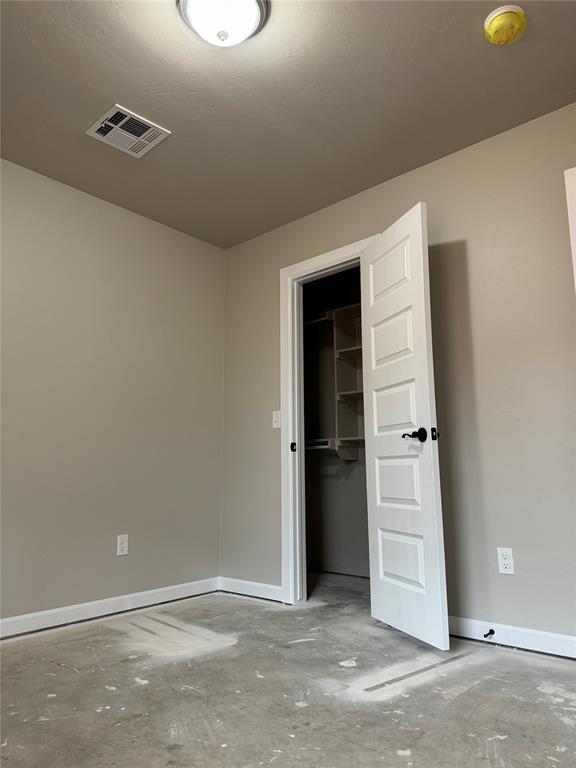 unfurnished bedroom featuring a spacious closet, a closet, and concrete floors