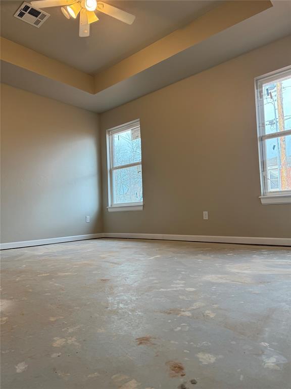 unfurnished room featuring concrete flooring, ceiling fan, and a tray ceiling