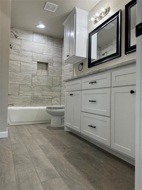 full bathroom featuring vanity, toilet, tiled shower / bath combo, and wood-type flooring