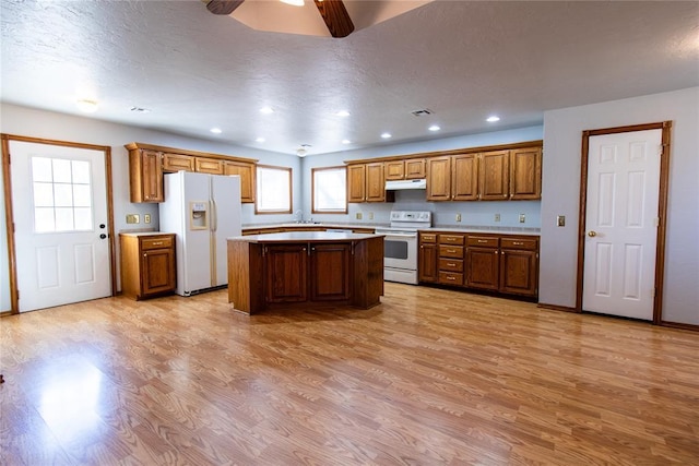 kitchen featuring sink, white appliances, a center island, light hardwood / wood-style flooring, and ceiling fan