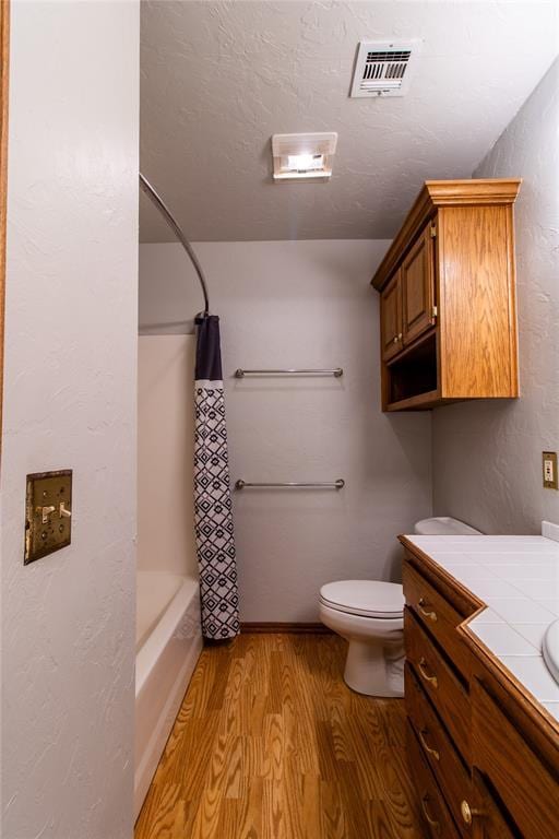 full bathroom featuring vanity, shower / tub combo, hardwood / wood-style flooring, and toilet