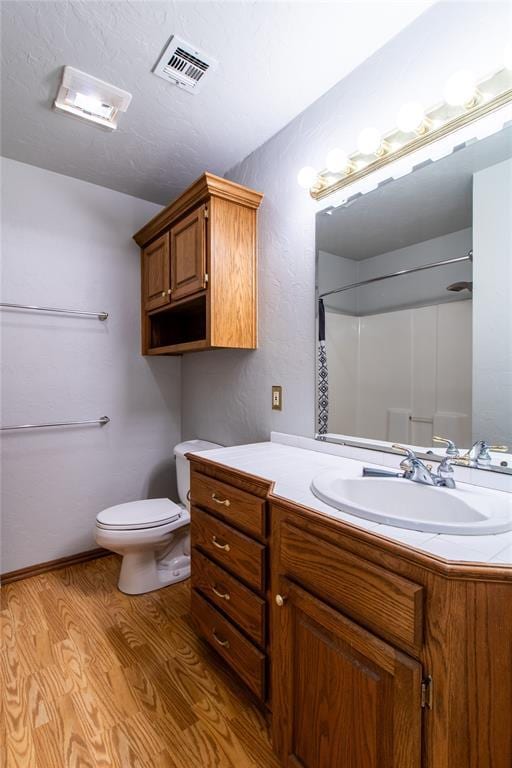 bathroom with vanity, wood-type flooring, a shower, and toilet