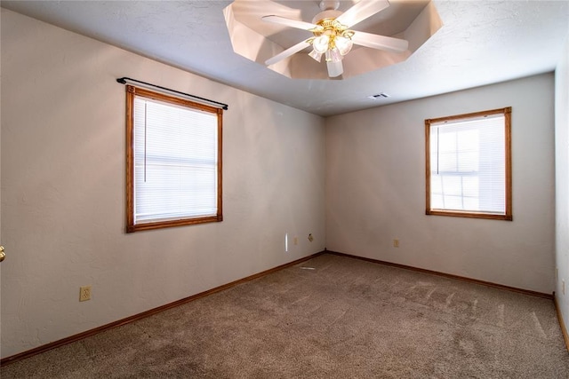 carpeted spare room featuring ceiling fan and a tray ceiling