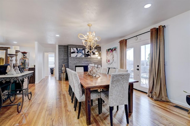 dining space with a fireplace, a chandelier, and light hardwood / wood-style floors