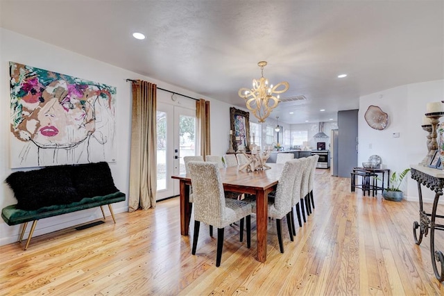 dining area with french doors, a notable chandelier, and light wood-type flooring