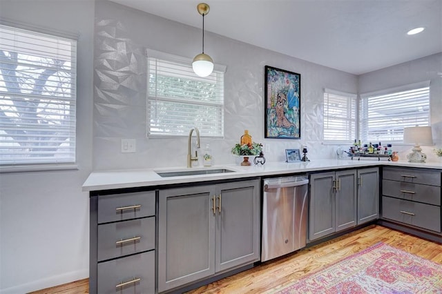 kitchen with sink, dishwasher, gray cabinetry, decorative light fixtures, and light wood-type flooring