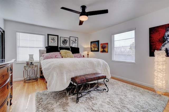 bedroom with ceiling fan, multiple windows, and light hardwood / wood-style flooring