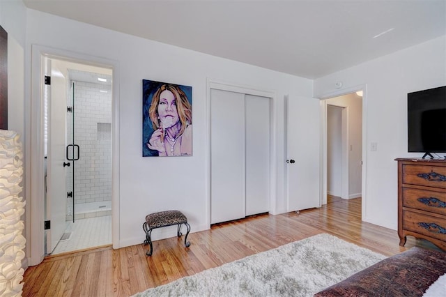 bedroom with ensuite bathroom, light hardwood / wood-style floors, and a closet