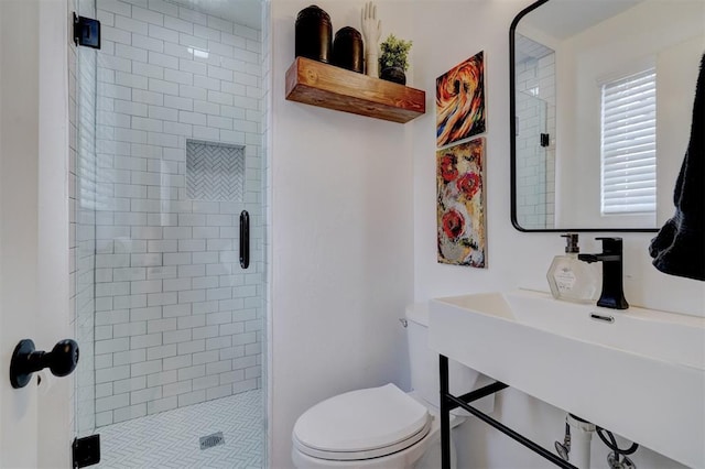 bathroom featuring sink, a shower with shower door, and toilet