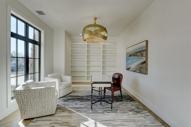 living area with a notable chandelier, built in shelves, and hardwood / wood-style flooring