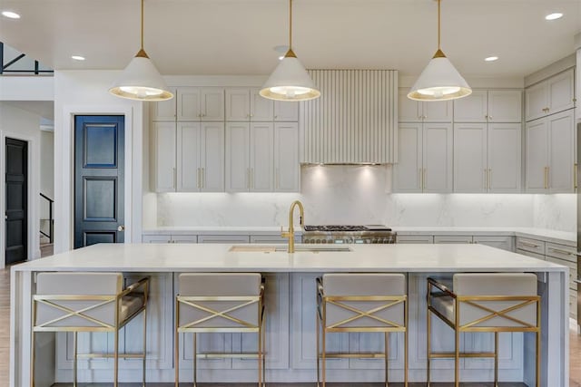 kitchen with a kitchen island with sink, decorative backsplash, a breakfast bar area, and decorative light fixtures