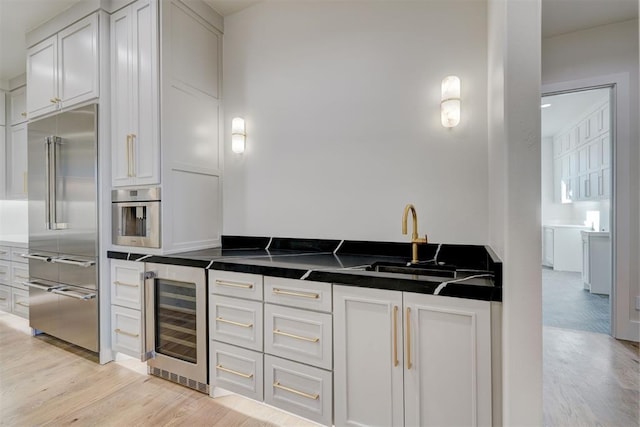 kitchen with stainless steel appliances, sink, white cabinets, and wine cooler