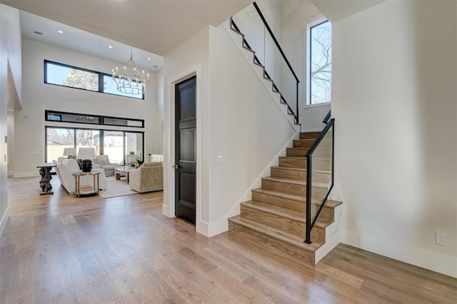 stairs with wood-type flooring, a chandelier, and a high ceiling