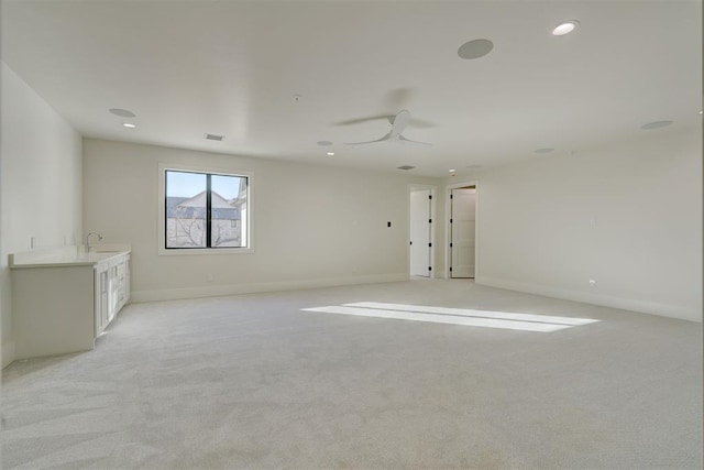 empty room featuring sink, light carpet, and ceiling fan