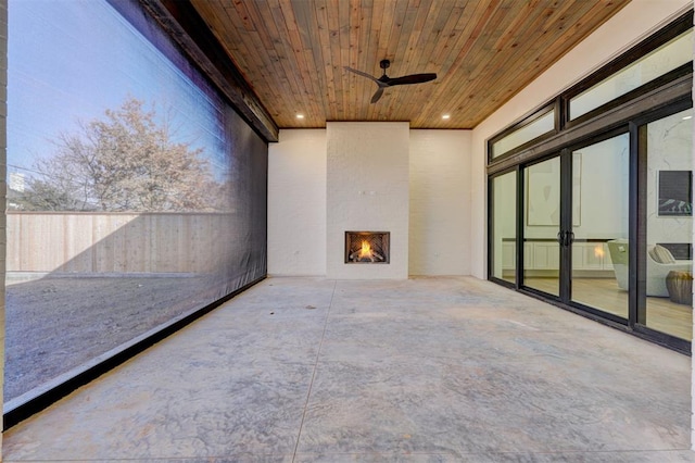 unfurnished sunroom with wood ceiling, a fireplace, and ceiling fan