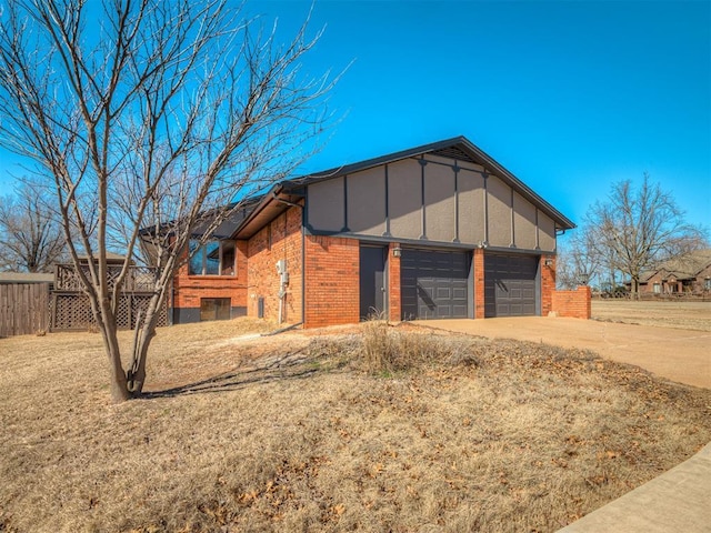 view of outbuilding featuring concrete driveway, an attached garage, and fence