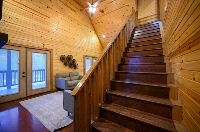 stairway with high vaulted ceiling, hardwood / wood-style flooring, wooden walls, and wooden ceiling