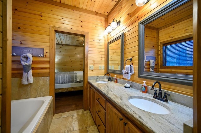 bathroom with vanity, a washtub, and wooden walls