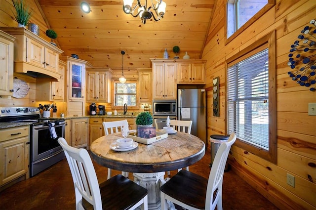 kitchen with vaulted ceiling, a wealth of natural light, wood walls, hanging light fixtures, and stainless steel appliances