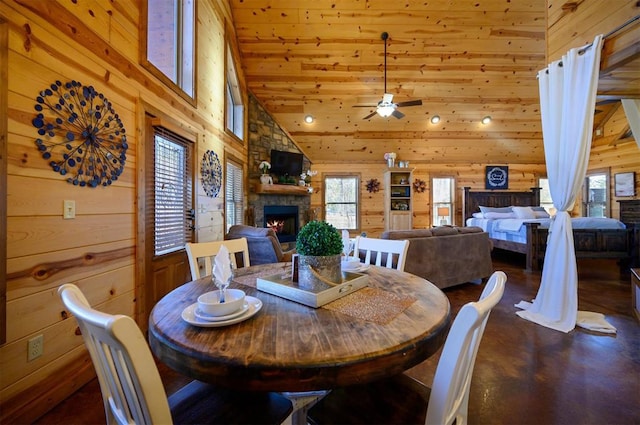 dining space with a fireplace, high vaulted ceiling, and wooden walls