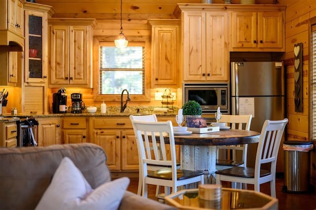 kitchen featuring hanging light fixtures, light stone countertops, sink, and appliances with stainless steel finishes