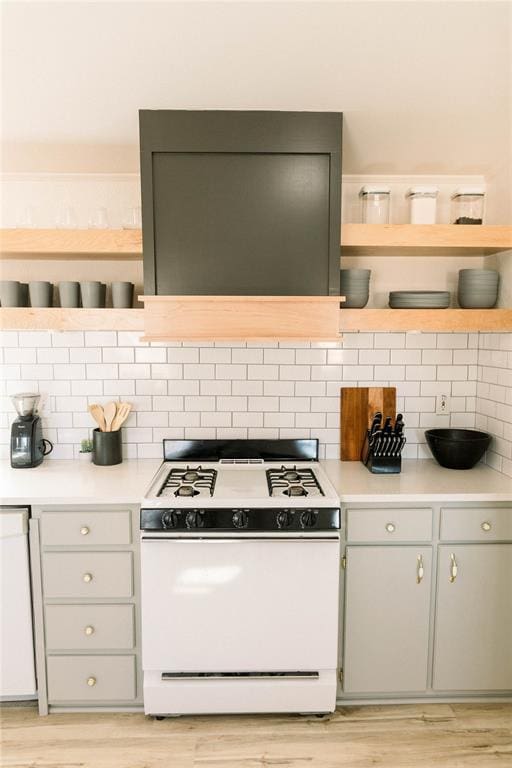 kitchen featuring tasteful backsplash, extractor fan, white range with gas stovetop, and light hardwood / wood-style flooring