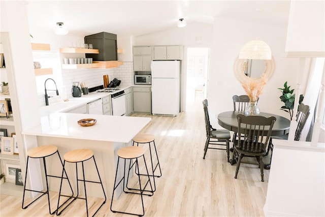 kitchen featuring gray cabinets, tasteful backsplash, lofted ceiling, sink, and white appliances