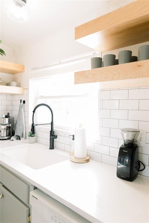 kitchen featuring tasteful backsplash, dishwasher, sink, and green cabinetry