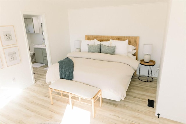 bedroom with ensuite bathroom and light hardwood / wood-style flooring