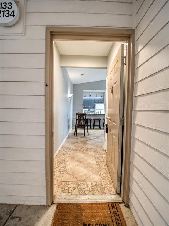 hall with lofted ceiling and wooden walls