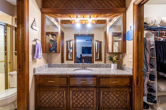 bathroom featuring a spacious closet, toilet, and vanity