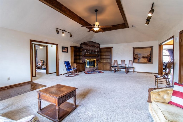 living room featuring track lighting, a fireplace, carpet flooring, ceiling fan, and vaulted ceiling with beams