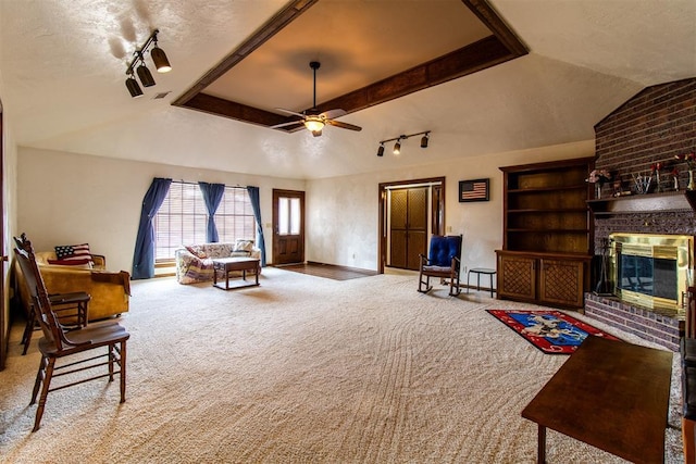 interior space featuring a brick fireplace, lofted ceiling, carpet flooring, rail lighting, and a textured ceiling