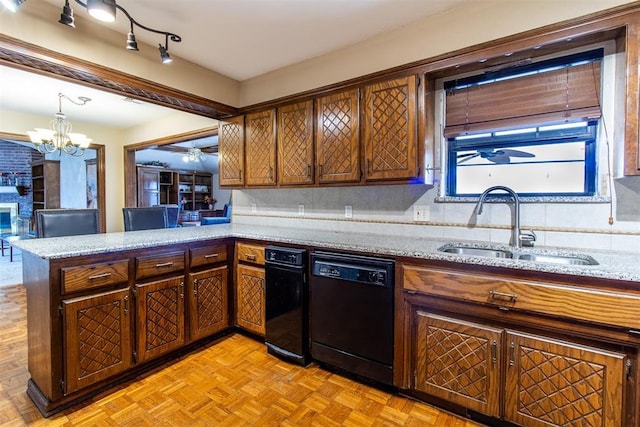 kitchen with light stone counters, a peninsula, a sink, dishwasher, and ceiling fan with notable chandelier