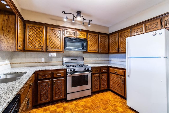 kitchen featuring stainless steel range with gas cooktop, black microwave, dishwasher, decorative backsplash, and freestanding refrigerator