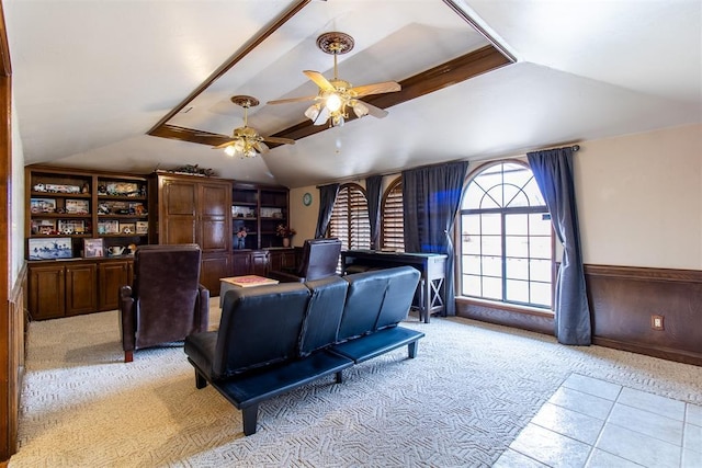 interior space with lofted ceiling, wainscoting, ceiling fan, wood walls, and light carpet