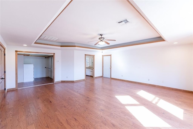 unfurnished bedroom featuring crown molding, hardwood / wood-style floors, ceiling fan, and a tray ceiling