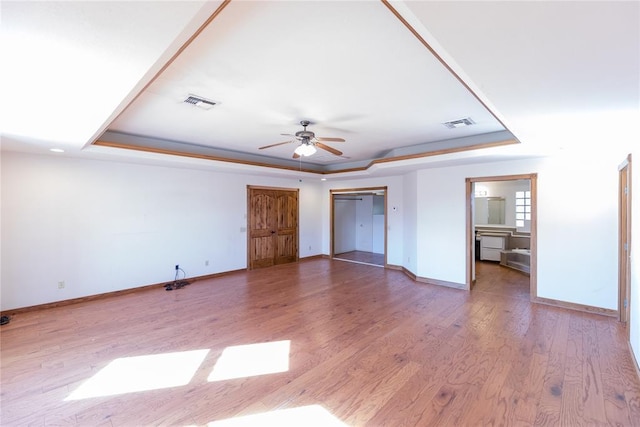 unfurnished bedroom featuring a raised ceiling, ceiling fan, and light wood-type flooring