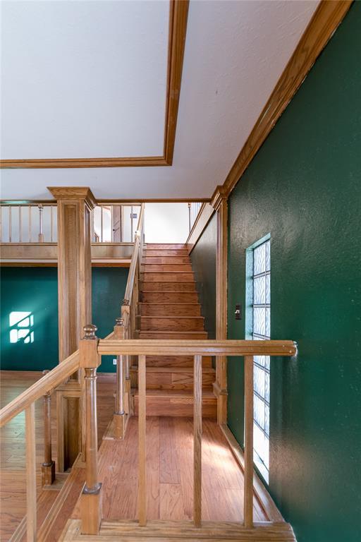 stairway with wood-type flooring and ornamental molding