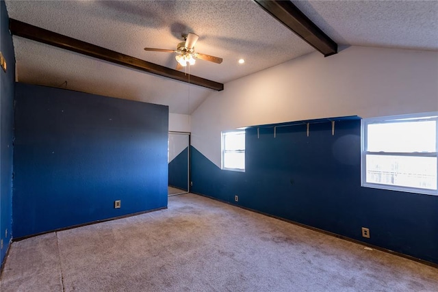 carpeted empty room with ceiling fan, a textured ceiling, and vaulted ceiling with beams