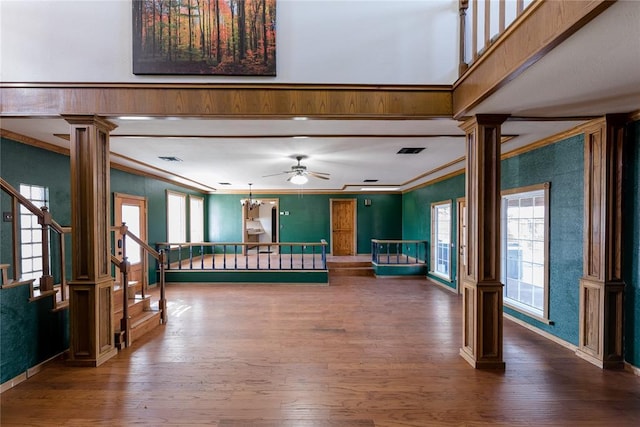 interior space with decorative columns, ornamental molding, wood-type flooring, and ceiling fan with notable chandelier