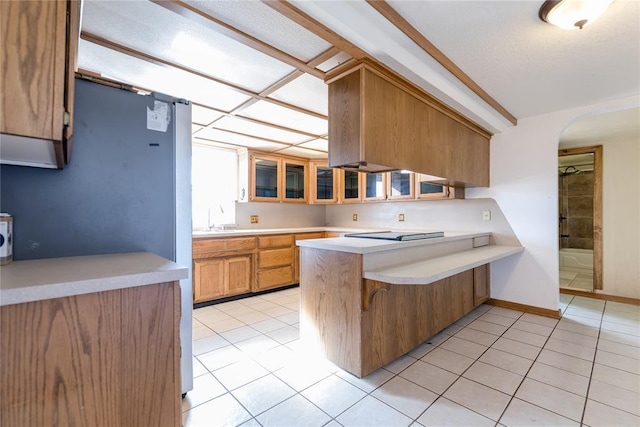 kitchen with light tile patterned flooring, sink, a kitchen bar, black electric stovetop, and kitchen peninsula