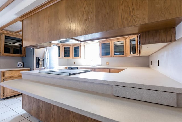 kitchen featuring stovetop, stainless steel refrigerator with ice dispenser, sink, and light tile patterned floors